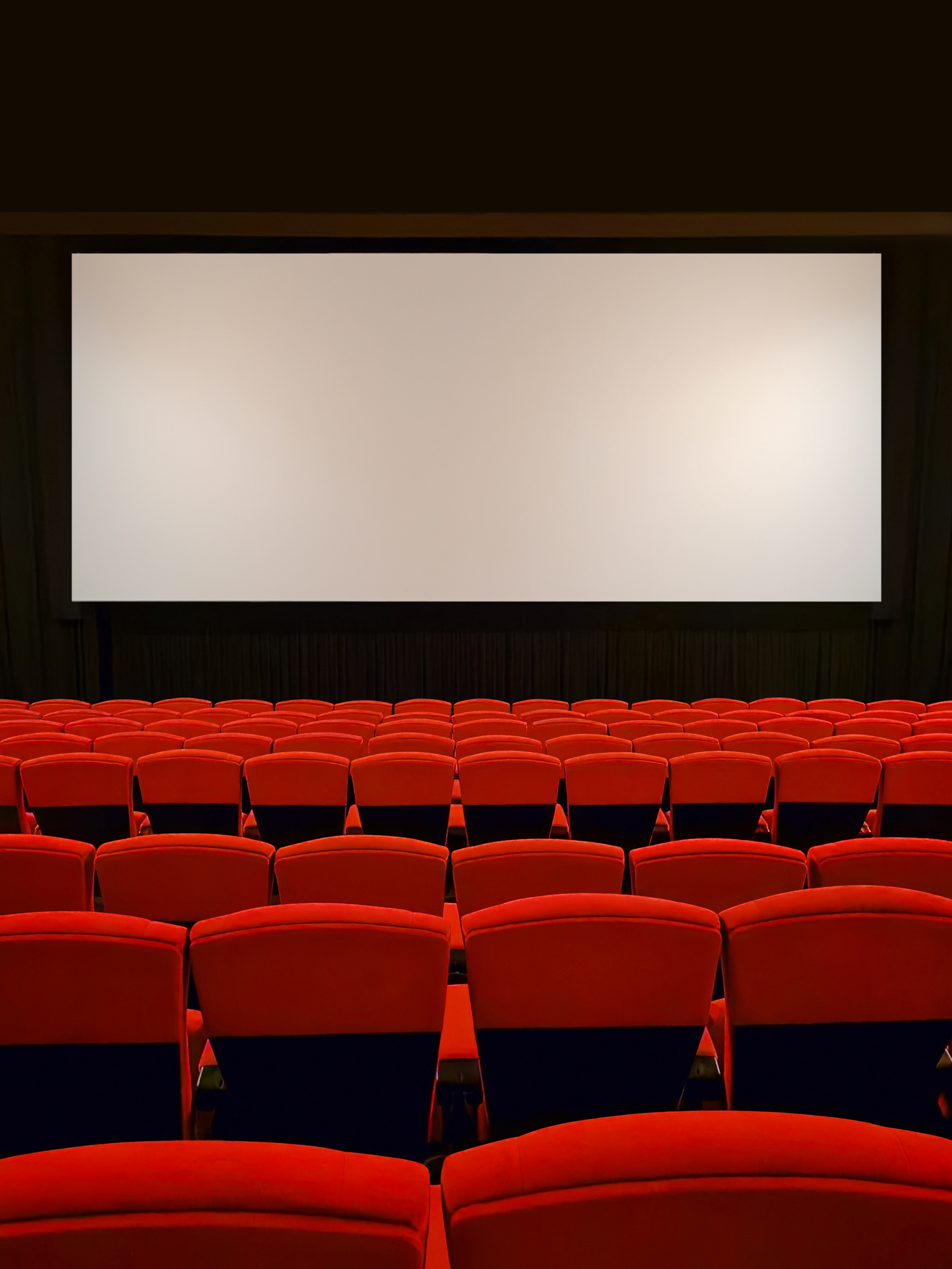 A row of neatly arranged red movie seats in an empty movie theater. Film industry.