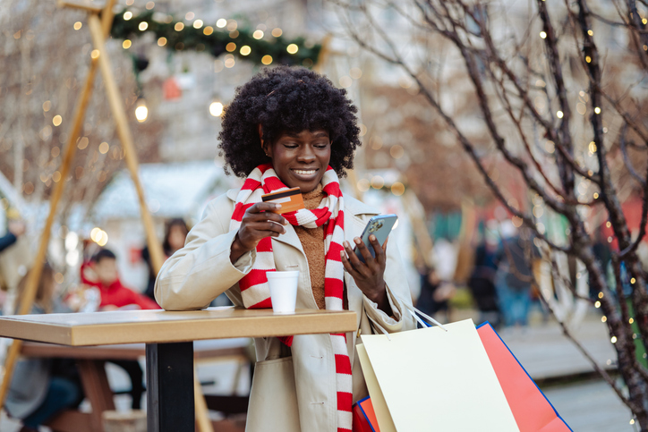 Woman enjoying holiday shopping with coffee and smartphone