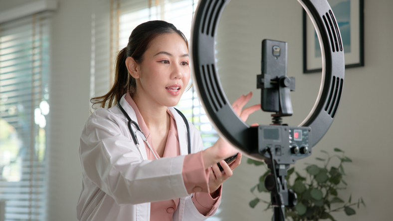 Young adult woman Gen Z asia people anti aging expert modern nurse live talk viral video selfie camera on mobile phone app mental health care. Online sharing digital virtual asian vlogger filming.