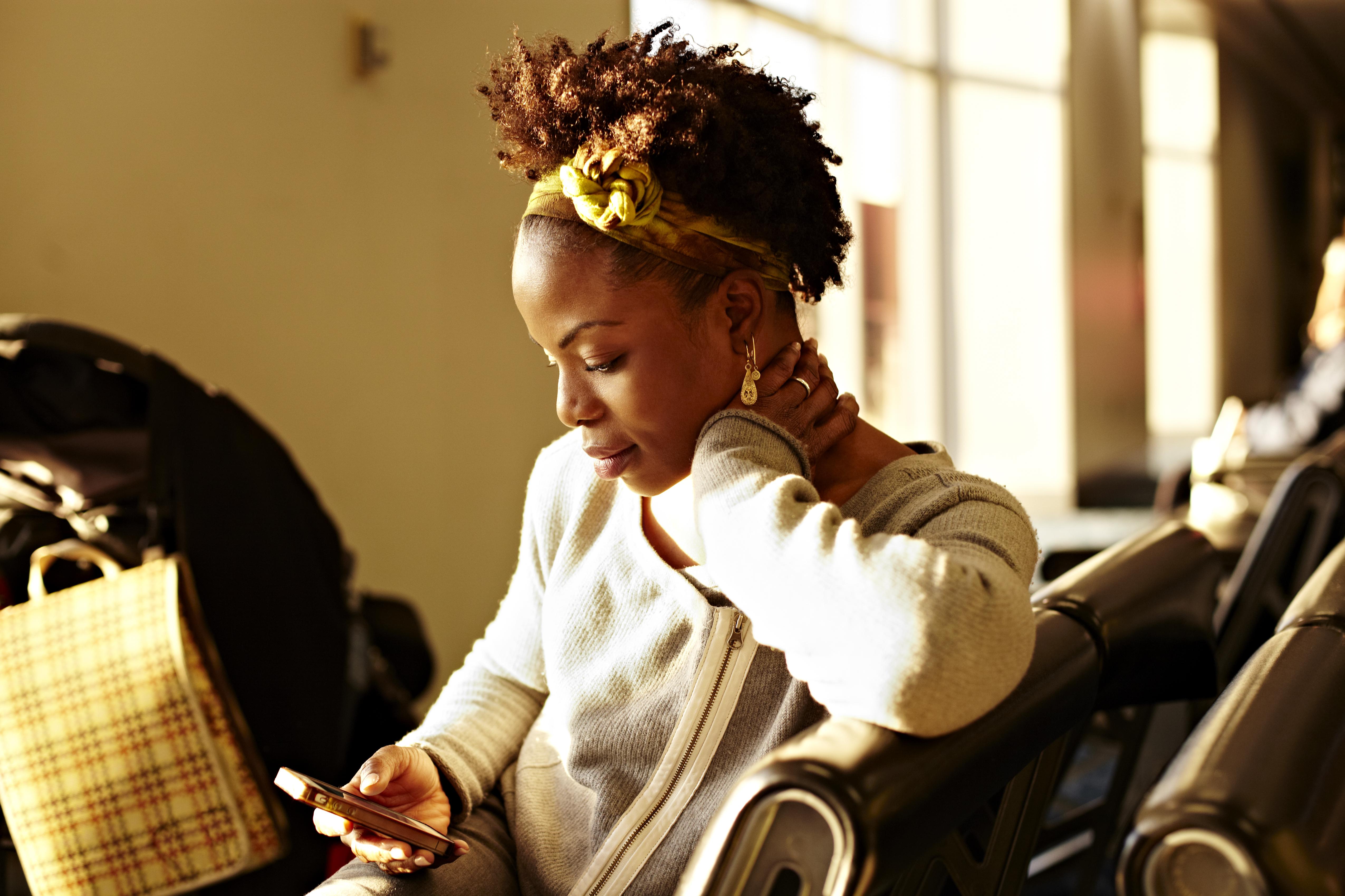Black woman using cell phone in airport
